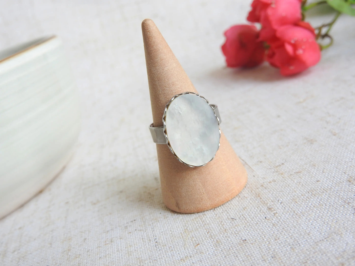 bague à anneau réglable en acier inoxydable argenté posée sur un cône en bambou. Bijou orné d'une pierre naturelle nacre blanche.