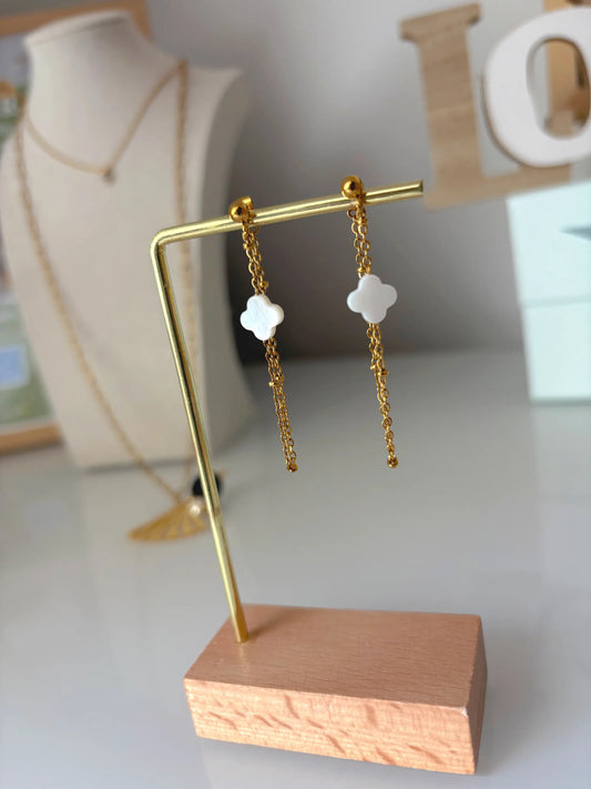 boucles d'oreilles chaînettes en acier inoxydable doré ornées d'une perle trèfle en nacre blanche. Bijou suspendu à un présentoir en métal doré et bambou.