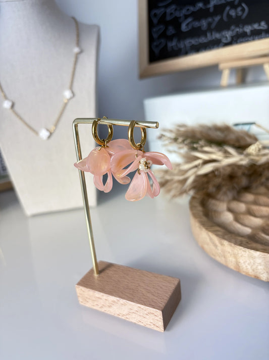 boucles d'oreilles mini-créoles en acier inoxydable doré, ornées de pétales formant un bouquet floral en acrylique couleur pêche. Bijou présenté sur un support métallique doré et bambou pour bijou.