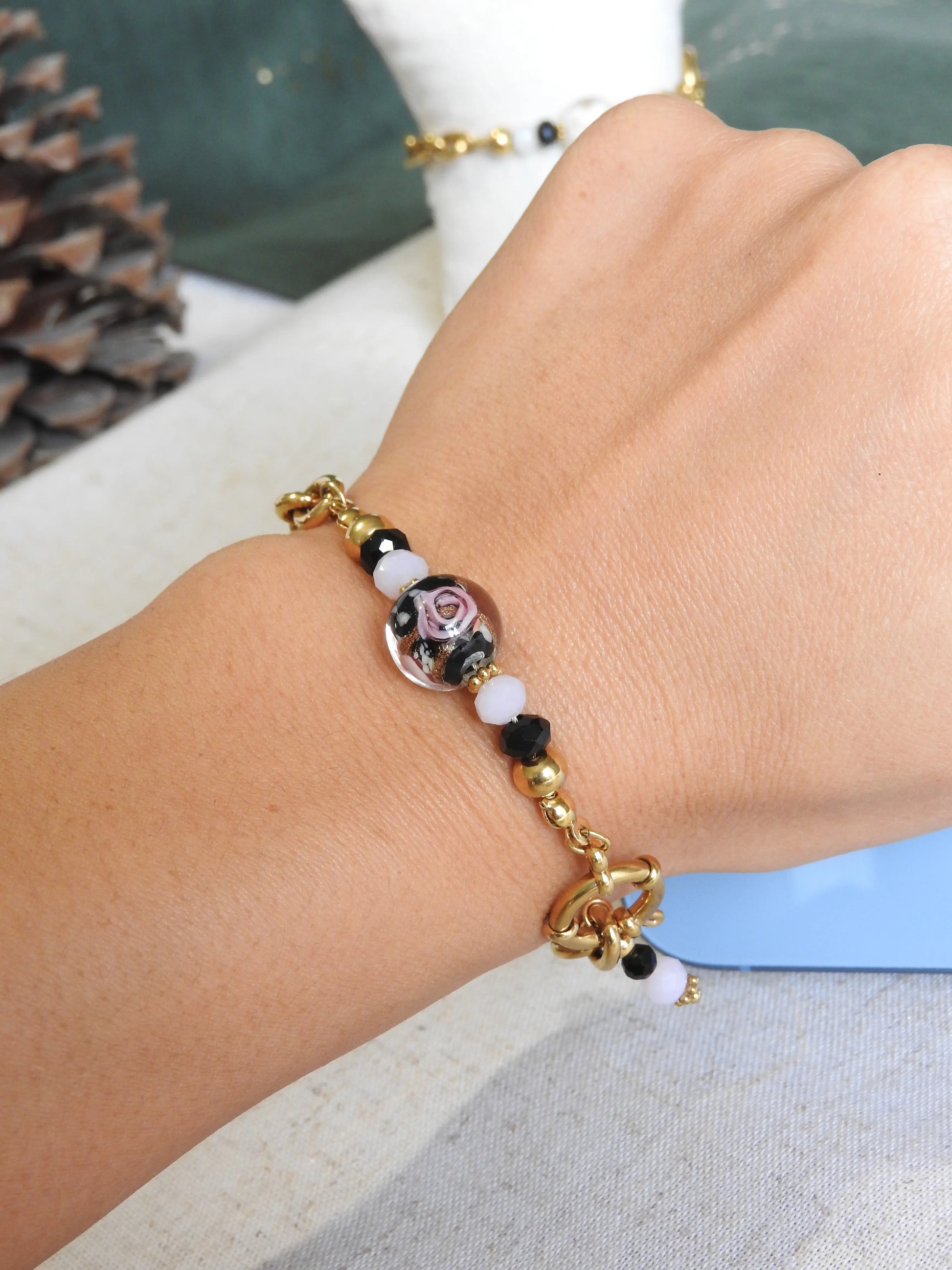 Bracelet mi-chaîne et mi-perles boule florale noire en verre. Bijou porté au poignet.