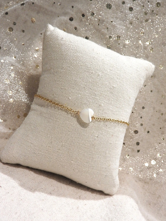 Bracelet chaîne fine en acier inoxydable doré orné d'une perle coeur en nacre blanche.
