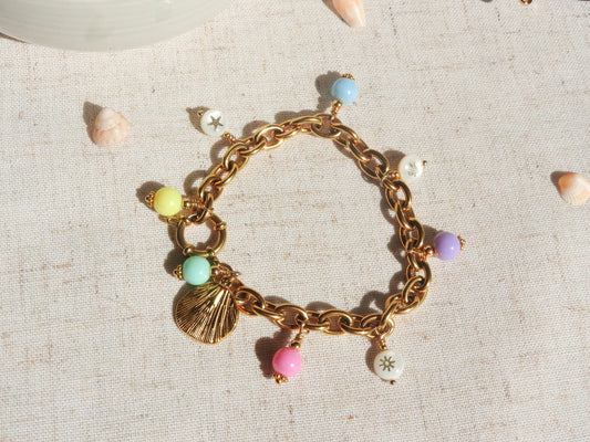 bracelet breloques à gros maillons en acier inoxydable doré. Breloques en perles colorées pastelles en acryliques, pendentif coquillage et perles en nacre blanche aux motifs étoile de mer, tortue de mer et soleil doré.