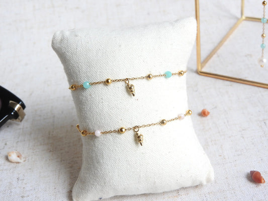 deux bracelets à chaines fines perlées en acier inoxydable et en verre, ornés d'une mini-breloque coquillage.