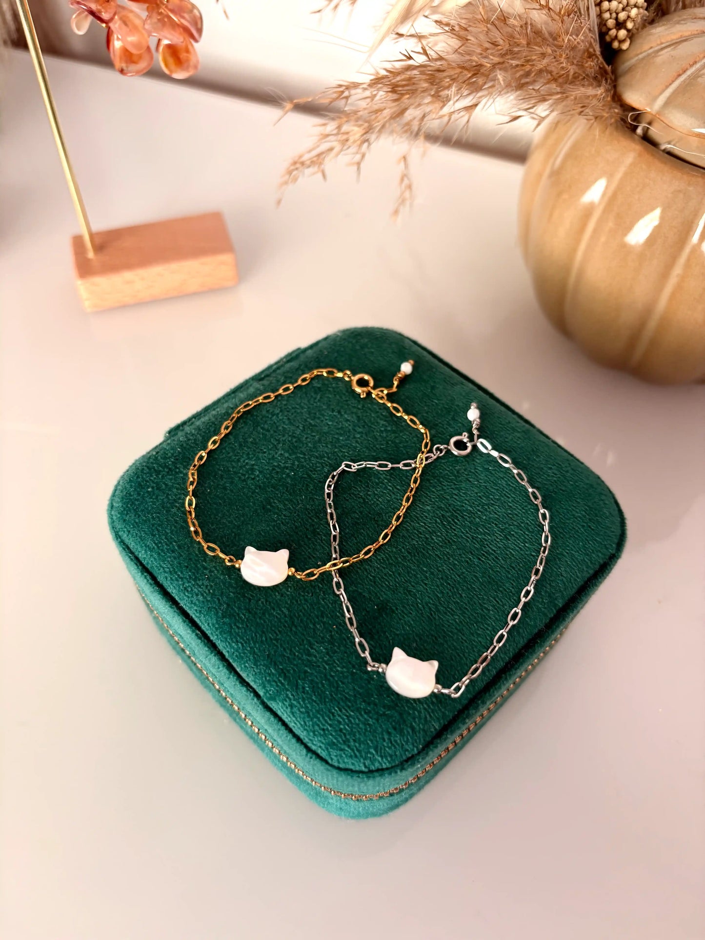 Deux bracelets superposés chaîne à maille rectangle en acier inoxydable doré et argenté. Bijoux ornés d'une perle chat en nacre blanche.