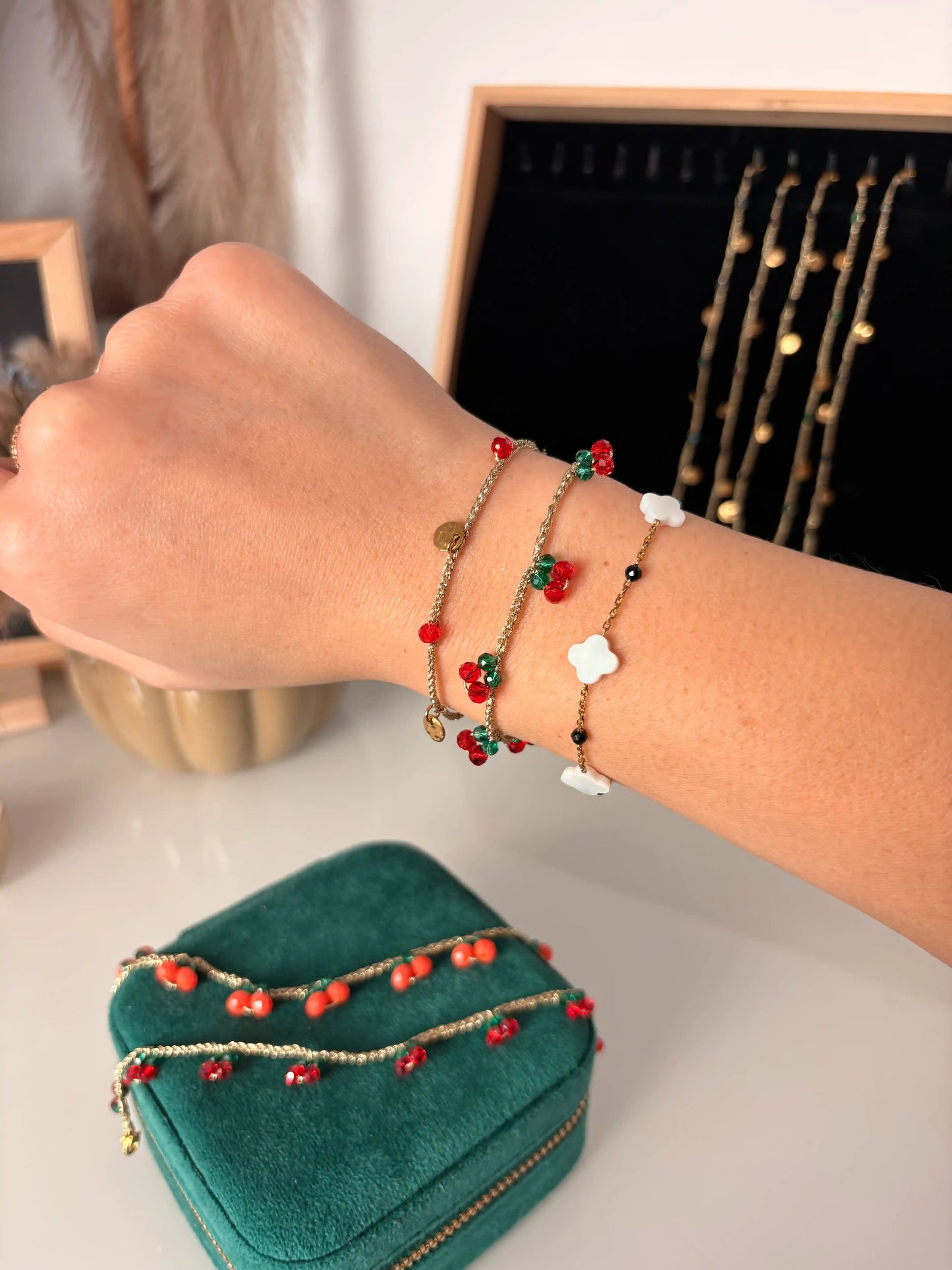 Bracelets portés en stacking au poignet en acier inoxydable doré et ornés de perles de verre colorées et en nacre blanche.