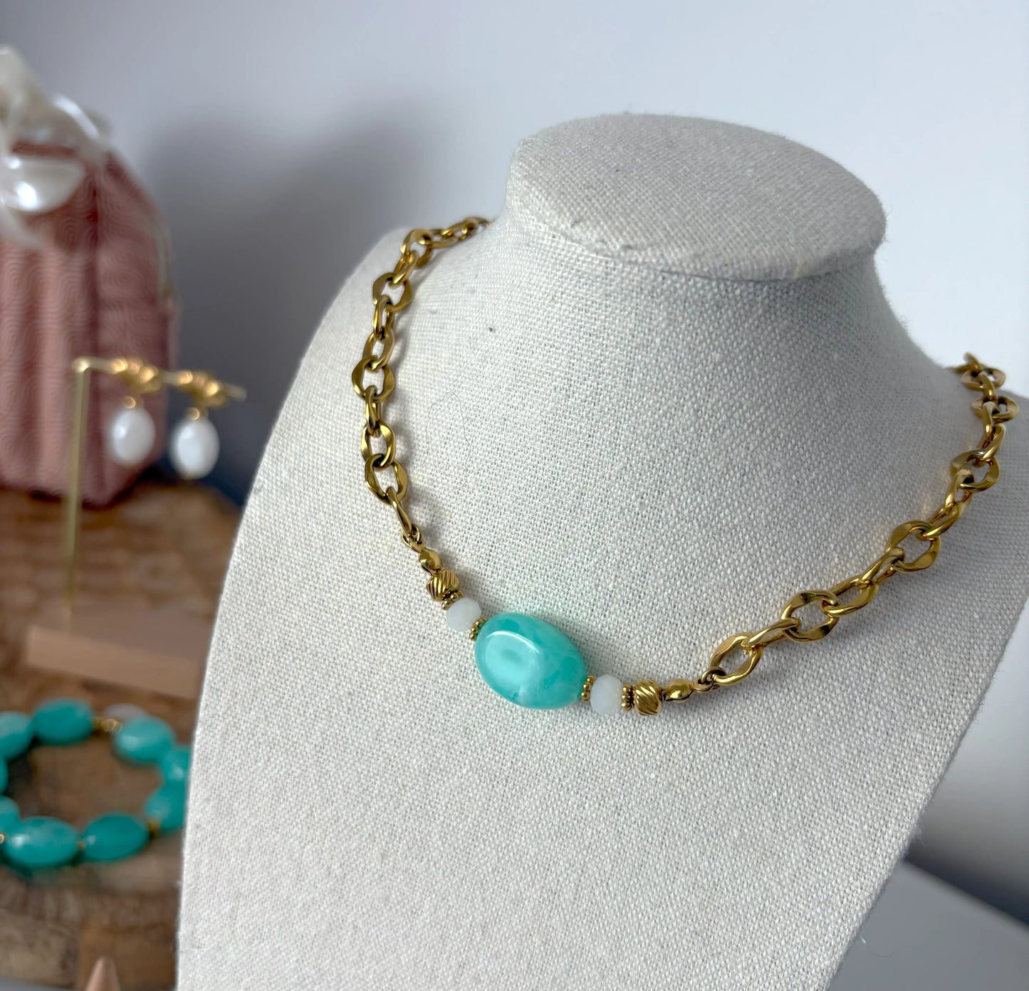 collier ras-de-cou chaine grosses mailles en acier inoxydable doré, orné d'une grande perle irrégulière de couleur turquoise. Bijou posé sur un buste présentoir.