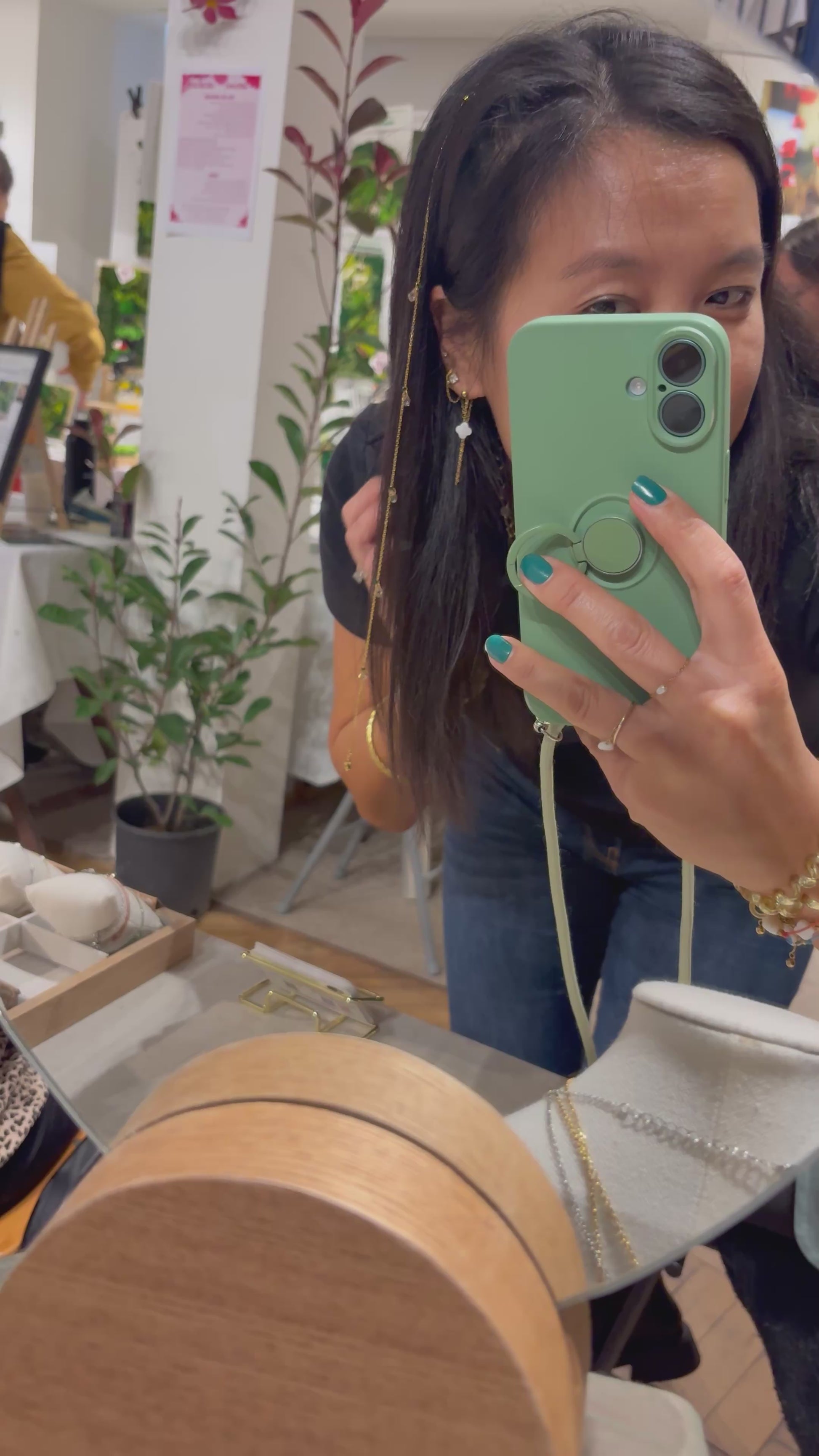 vidéo présentant le créatrice de bijoux de la marque M'Joy Creation qui porte un bijou pour les cheveux, composé d'une barrette noire associée à une chaîne en acier inoxydable doré et orné de perles goutte en cristal beige.