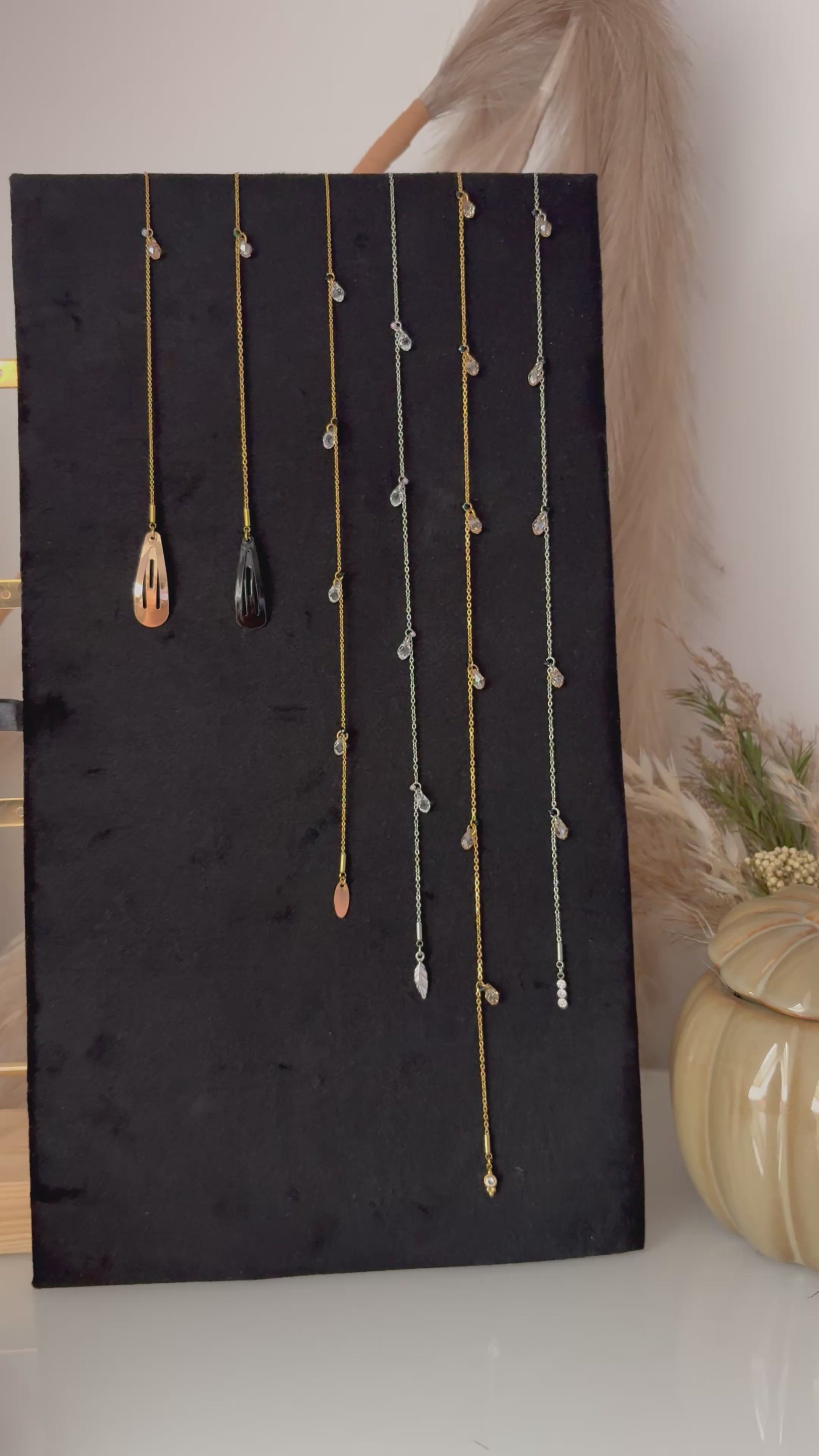 vidéo présentant des bijoux pour les cheveux avec barrette noire et dorée associée à une chaîne en acier inoxydable doré ou argenté, ornée de perles goutte en cristal et d'une breloque de finition.