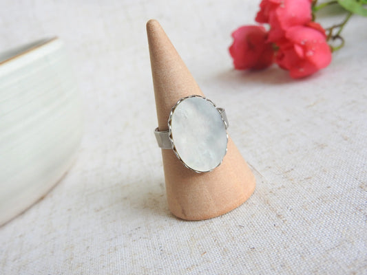 bague à anneau réglable en acier inoxydable argenté posée sur un cône en bambou. Bijou orné d'une pierre naturelle nacre blanche.