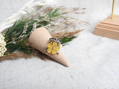 bague à anneau fin réglable en acier inoxydable doré posé sur un cône en bambou, posé sur un mini-bouquet de fleurs. Bijou orné de breloques fleurs en nacre jaune et marron et de perles de verre et en acier inoxydable doré.