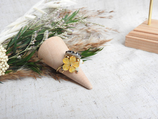 bague à anneau fin réglable en acier inoxydable doré posé sur un cône en bambou, posé sur un mini-bouquet de fleurs. Bijou orné de breloques fleurs en nacre jaune et marron et de perles de verre et en acier inoxydable doré.