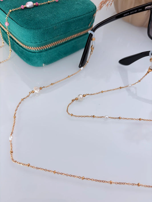 Bijou chaîne de lunettes en acier inoxydable doré et perlée, ornée de perles d'eau douce blanche nacré. Bijou monté sur une monture à lunettes