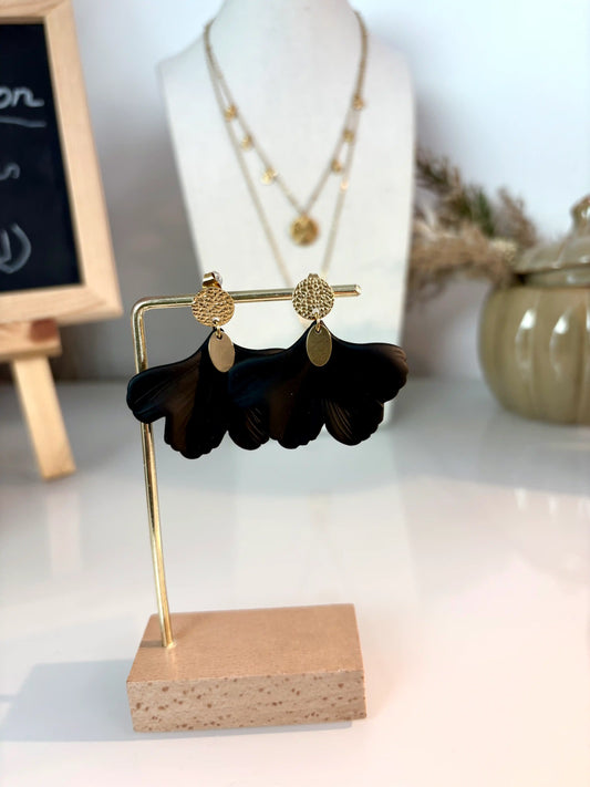 boucles d'oreilles feuille ginkgo noire à disque martelé en acier inoxydable doré et sequin ovale. Bijoux présentés sur un support métallique doré et bambou, posé sur une table décorée d'un pot citrouille en céramique