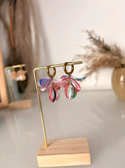 boucles d'oreilles mini-créoles en acier inoxydable doré et décorées de pétales sequins multicouleurs et perles de verre lilas. Bijoux présentés sur un support métallique doré et bambou.