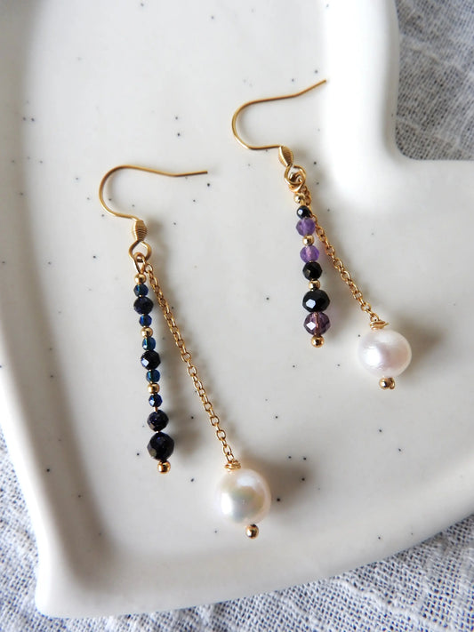 Boucles d'oreilles disposées sur une coupelle céramique blanche. Boucles duo avec barre en perles de verre colorées et perle d'eau douce suspendue à une chainette en acier inoxydable doré.