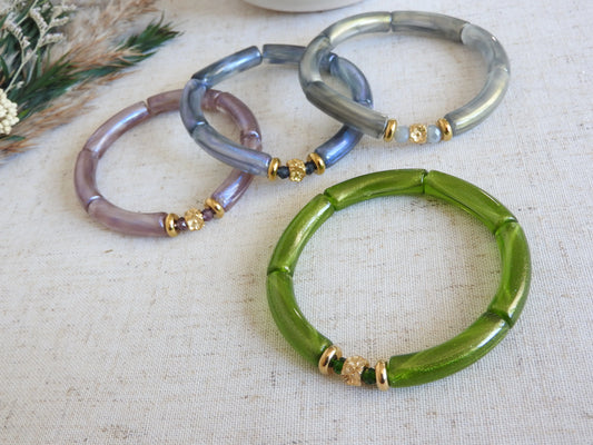 quatre bracelets joncs élastiqués en perles tube colorées vert, gris, bleu et parme irisés. Bijoux ornés de perles de verre et perles rondelle et cube au motif fleuri en acier inoxydable doré.