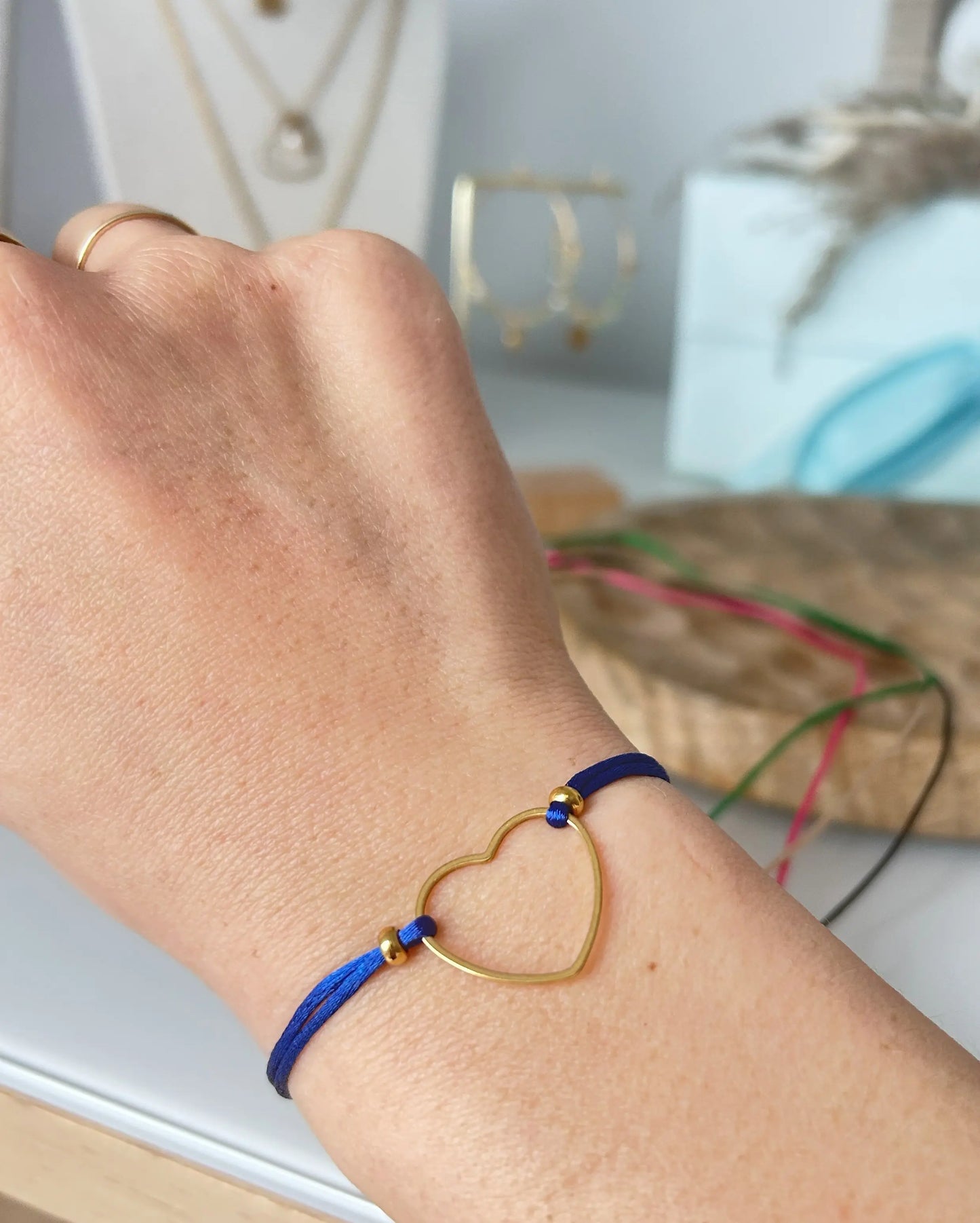 bracelet cordon ajustable en nylon bleu roi orné d'un cœur lisse en acier inoxydable doré. Bijou porté au poignet.