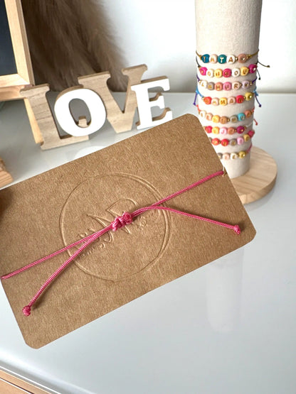 bracelets cordons colorés à noeuds coulissants présentés sur un carton kraft. Bijou à message à personnaliser avec des perles colorées.