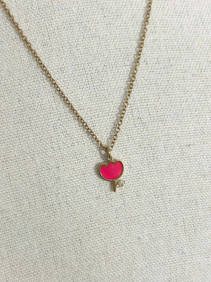 Collier pour enfant à chaîne fine posé à plat sur une nappe beige. Bijou orné d'un pendentif tulipe rouge en résine époxy et acier inoxydable doré. 