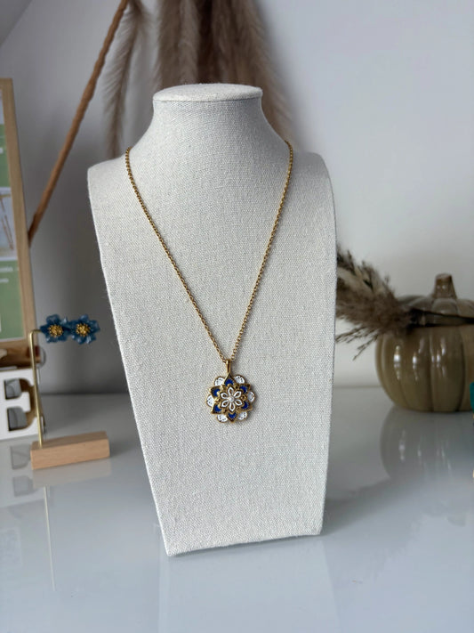 Collier sautoir en acier inoxydable doré présenté sur un buste présentoir. Bijou orné d'un pendentif mandala bleu et blanc en résine époxy et en acier inoxydable doré.