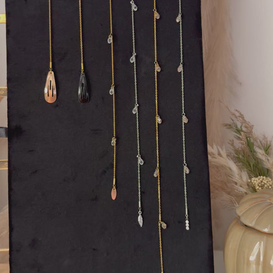 vidéo présentant des bijoux pour les cheveux avec barrette noire et dorée associée à une chaîne en acier inoxydable doré ou argenté, ornée de perles goutte en cristal et d'une breloque de finition.